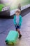 Travel concept. A boy with a suitcase. Beautiful child with a turquoise suitcase in a green sweater is ready to travel