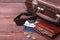 Travel concept with Vintage suitcase, sunglasses, old camera, suede boots, case for money and passport on wooden floor.