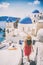 Travel destination europe tourist girl walking in Santorini at the three blue domes, famous Greek landmark. Oia village