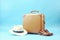 Travel essentials suitcase with hat, sunglasses, passport, and slippers on blue background