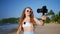 Travel influencer records beach vlog with pro camera, wireless lav mic. Female blogger captures scenic coast, shares