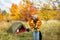 Travel, love and autumn concept - couple in love posing near green tent in autumn forest