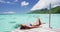 Travel luxury vacation destination bikini woman sunbathing at overwater bungalow