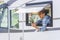 Travel and mobile roaming phone connection. One modern woman staying outside the window of her camper van rv and using cellphone