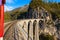 Travel with the red Rhaetian railway sightseeing train Bernina Express running over Landwasser Viaduct