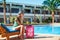 Travel, summer holidays and vacation concept - Beautiful woman walking near hotel pool area with red suitcase in Egypt