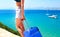 Travel theme. Woman with suitcase by the sea close-up.