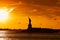 Travel to Manhattan, visit New York. Amazing summer sunset over Statue of Liberty with spectacular dramatic sky.