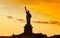 Travel to Manhattan, visit New York. Amazing summer sunset over Statue of Liberty with spectacular dramatic sky.