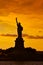 Travel to Manhattan, visit New York. Amazing summer sunset over Statue of Liberty with spectacular dramatic sky.