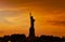 Travel to Manhattan, visit New York. Amazing summer sunset over Statue of Liberty with spectacular dramatic sky.