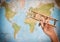 Travel and tourism concept. hand holding toy airplane against map of world