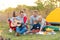 Travel, tourism, hike, picnic and people concept - group of happy friends with tent and drinks playing guitar at camping