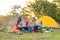 Travel, tourism, hike, picnic and people concept - group of happy friends with tent and drinks playing guitar at camping