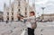 Travel tourist woman feeds doves near Duomo di Milano - the cathedral church of Milan in Italy. Girl enjoying on the square in the