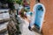 Travel tourist woman on vacation in Greece. Person with blue sunhat in front of traditional Mediterranean house. Colored