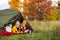 Travel, trekking and hiking concept - portrait of couple drinking tea or coffee in tent in autumn forest