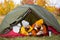 Travel, trekking and hiking concept - portrait of couple drinking tea in tent in autumn forest