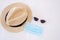 Travel under Covid-19 and new normal concepts. medical face mask, sunglasses and beach hat on white bed, prevent coronavirus or