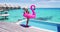 Travel. Vacation woman in bikini with inflatable pink flamingo float pool toy by swimming pool. Elegant lady relaxing