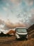 Travel vehicle concept with modern camper van motor home parked free in tha nature with mountains and sunset in background. Summer