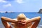 Travel, vocation, holiday concept. Woman in hat is lying on deckchair on beach by sea.