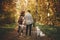 Travel and Wanderlust. Stylish couple standing with cute dog in sunny autumn woods. Young  hipster family hiking with swiss