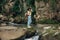 Travel and wanderlust. Stylish woman traveler with backpack relaxing at river in mountains, smiling
