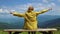 Travel woman hiker raise hands sits on mountain cliff in summer sunny day. Beautiful mountains landscape view