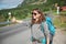 Travel woman hitchhiking. Backpacker on road. Happy smiling gorl with big backpack, Norway