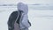 Travel of woman on ice of Lake Baikal. Trip to winter island. Girl is walking at foot of ice rocks. Traveler looks at