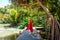 Travel woman in red dress relax in tropical resort. Female traveler on exotic summer vacation. Girl in straw hat walking