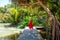 Travel woman in red dress relax in tropical resort. Female traveler on exotic summer vacation. Girl in straw hat walking