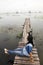 Traveler asian woman posing sitting on the wooden brigde and travel Pakpra canal at Ban Pak Pra fishing village