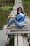 Traveler asian woman posing sitting on the wooden brigde and travel Pakpra canal at Ban Pak Pra fishing village