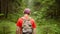 A traveler with a backpack and a cap is walking along a forest path, back view, camera tracking