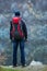 Traveler with a backpack is standing against the gray granite wa