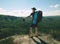 Traveler with backpack and sticks looks on  mountain peak