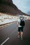 Traveler with backpack walks in the center of an epic winding road. Huge volcanic mountains in the distance behind him