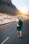 Traveler with backpack walks in the center of an epic winding road. Huge volcanic mountains in the distance behind him