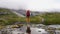 traveler with a big red backpack stopped near the lake enjoys the view of the foggy tops of the mountains