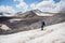 Traveler in a cap and sunglasses with a backpack on his shoulders in the snowy mountains on the glacier against the sky