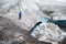 Traveler in a cap and sunglasses is sitting in the snowy mountains on the glacier. Traveler in a natural environment