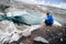 Traveler in a cap and sunglasses is sitting in the snowy mountains on the glacier. Traveler in a natural environment