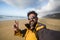 Traveler cheerful happy people man taking a selfie picture in a wild scenic place lonely beach with mountains in backgorund -