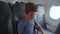 Traveler child boy flying in airplane inside wearing face mask. Virus outbreak quarantine passenger traveling pandemic