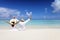 A traveler couple with raised arms sits on the beach and enjoys the tropical scenery