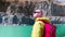 Traveler examines the area. View from the back. Stylish guy with a red backpack dressed in a yellow raincoat stands