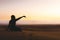 Traveler explorer girl sit in Desert and let sand fall from the hand.Silhouette of woman playing with sand on sunset in summer