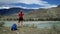 Traveler girl with backpack and cap reaches to the edge of the mountain and taking photo. Back view, slider